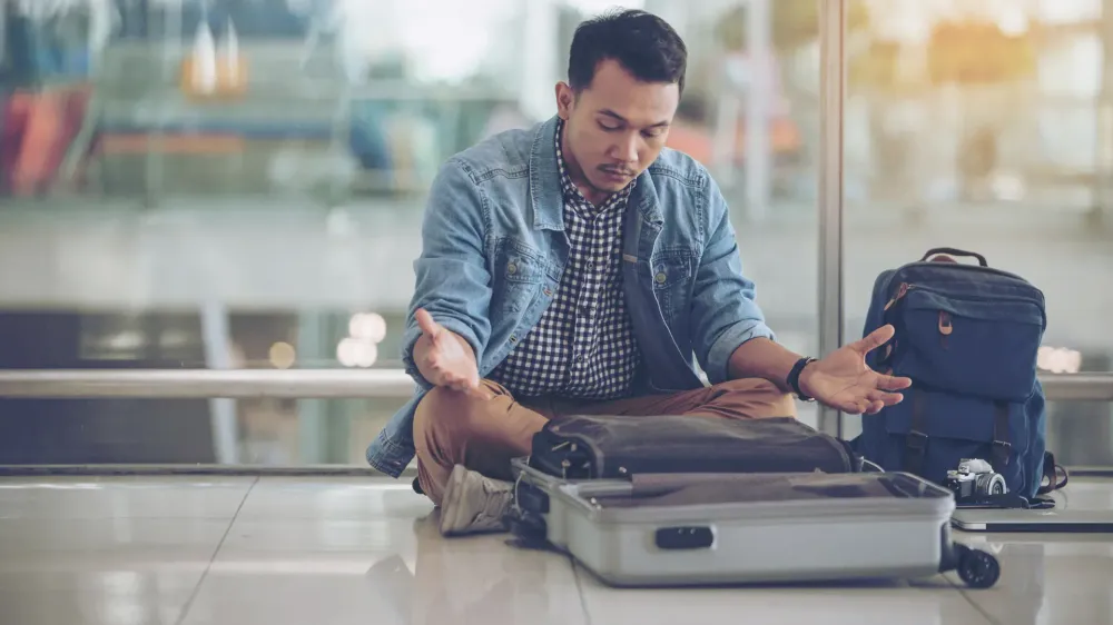 man looking at empty suitcase worried